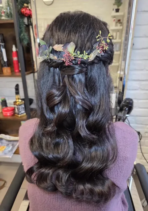 Halb hochgesteckte Brautfrisur mit geflochtenem Band, Locken und eingearbeiteten Blüten
