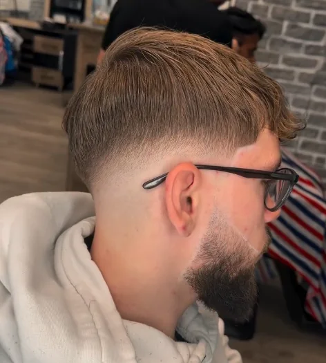 Herrenschnitt mit sauberem Skin-Fade und exakt konturiertem Bart, seitlich fotografiert